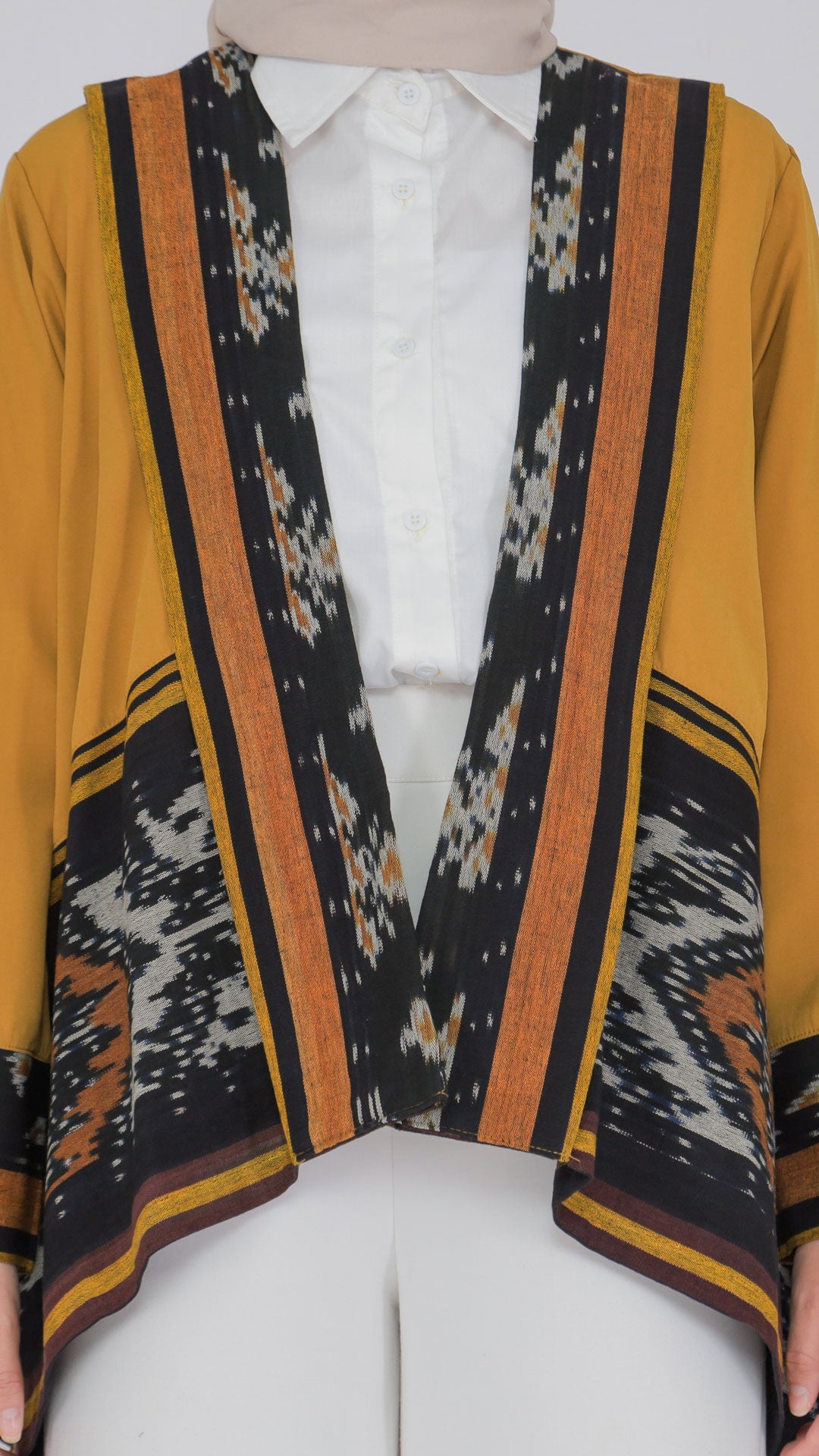 Traditional patterned garment over a white shirt on a mannequin